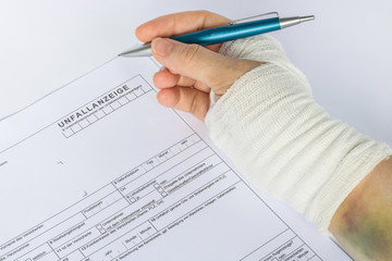 Frau mit verbundener Hand füllt Unfallanzeige aus