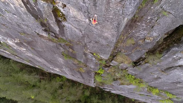 Aerial of Experienced Rock Climber at Dangerous Heights on Mountain Cliff Above Forest