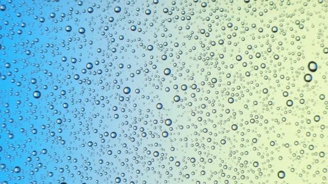Water drops on glass surface on blue and yellow