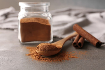 Wooden spoon with powdered cinnamon on table