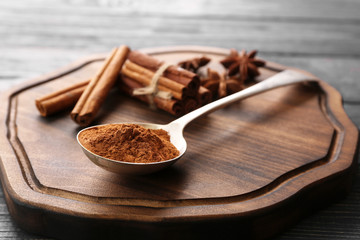 Cutting board with metal ladle, cinnamon sticks and powder on wooden table