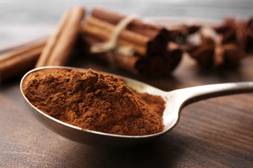 Metal ladle with powdered cinnamon on table, closeup