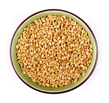 Wheat grains in bowl on white background, top view