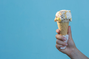 Ice cream cones in the hand of a girl on azure background