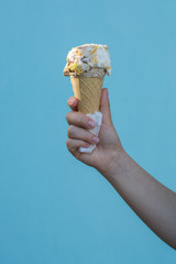 Ice cream cones in the hand of a girl on azure background