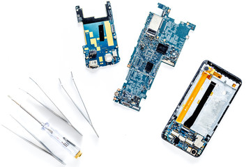 Parts of disassembled cell phone and screwdrivers on white background top view