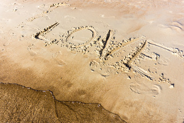 Love written in the sand on a sunset beach