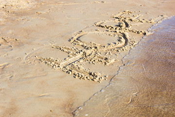 Hope written in the sand on a sunset beach