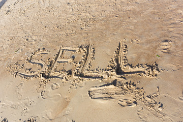 Sell written in the sand on a sunset beach