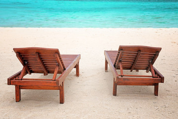 Obraz na płótnie Canvas Wooden sun loungers on sea beach in summer day