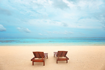 Fototapeta na wymiar Wooden sun loungers on sea beach in summer day