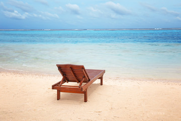 Fototapeta na wymiar Wooden sun lounger on sea beach in summer day