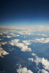 Clouds, blue sky and the wing of a jet passenger plane photo from the porthole. Travel and flights by plane.