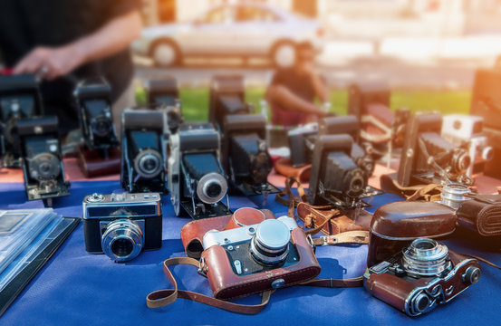 Old cameras are sold at a street market on a Sunny day.