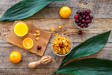 Vegetarian summer breakfast. Oranges, cherry and muesli on wooden table background top view
