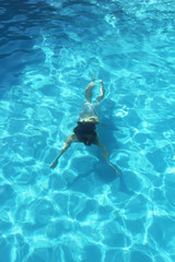 Young girl swimming underwater in the clear water of the pool