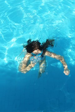 Young girl dives in the blue water of the pool