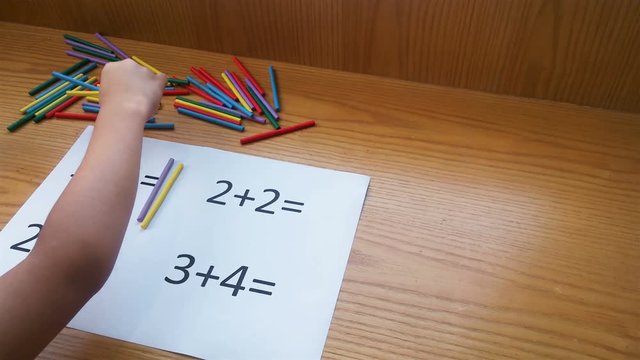 kid doing simple additions by counting numbers of sticks 