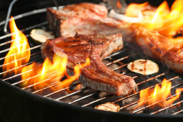 Delicious steak on grilling grid and flame, closeup