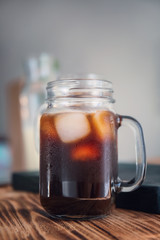 Mason jar with cold brew coffee and ice on wooden table