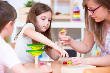 Preschool Teacher and Kids Playing with Wooden Toy Building Blocks