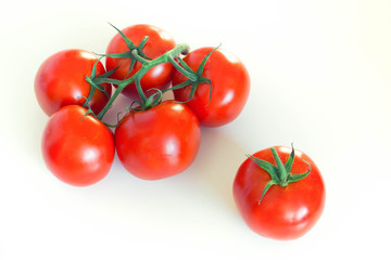 Bunch of fresh tomatoes on a twig, over white background