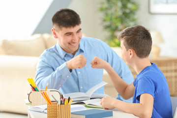 Obraz premium Father and son doing homework together indoors