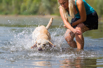 mature woman plays with a labrador in the lake