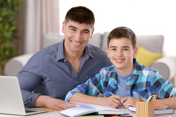 Father and son doing homework together indoors