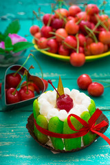 Creamy cake with cherries. Wooden turquoise background. Top view. Close-up