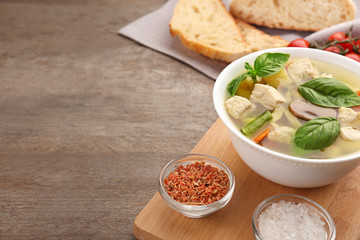 Composition with homemade turkey soup in bowl on wooden table