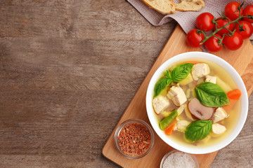 Composition with homemade turkey soup in bowl on wooden table