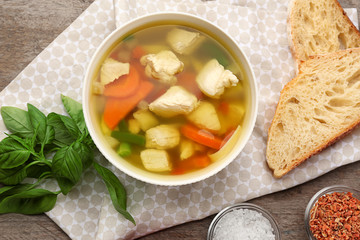 Composition with homemade turkey soup in bowl on wooden table