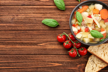 Composition with homemade turkey soup in bowl on wooden table