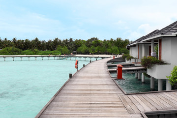 Naklejka premium View of wooden pontoon and modern beach houses on piles at tropical resort