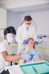 A dentist with an assistant treats the patient