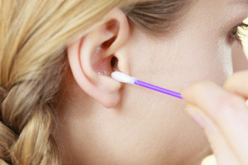 Woman cleaning ear with cotton swabs closeup