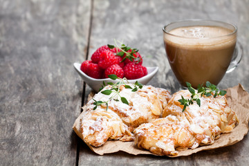 homemade  fresh almond croissant with cup of cappuccino on rustic wooden table