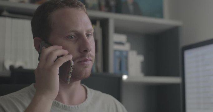Man has a negative conversation on the phone in his home office.
