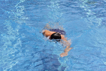 Strong muscular man swimming in pool crawl style. Active summer holiday vacation. Sport, healthy lifestyle concept