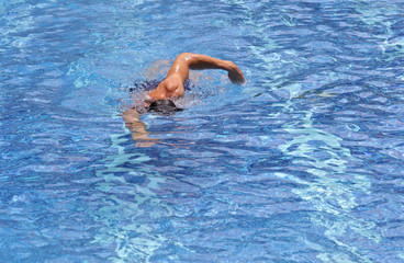 Strong muscular man swimming in pool crawl style. Active summer holiday vacation. Sport, healthy lifestyle concept