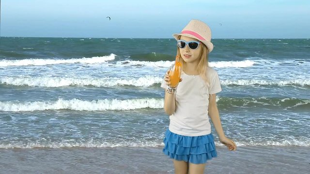 Young caucasian girl standing and drinking orange juice cocktail through straw. Sea coast horizon. Girl drinking orange juice. Vacation. Have same clip with transparent background Alpha Channel.