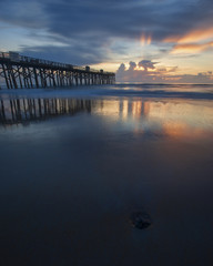 Fototapeta na wymiar Reflection of sunrise on wet sand.