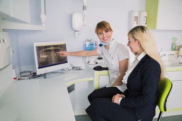 Dentist shows a patient x-ray of teeth in computer
