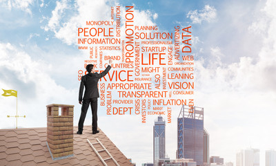 Young businessman standing on house roof and writing leadership skill concept. Mixed media