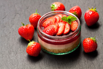 Mini  strawberry cheesecake in a glass pot on black stone background