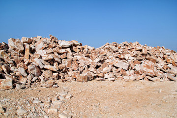 Brown Granite. Big pile of rocks for construction and boulders piled in a heap under a blue sky in summer time. A large pile of limestone in quarry. Pile of gravel and construction material. © zoranlino