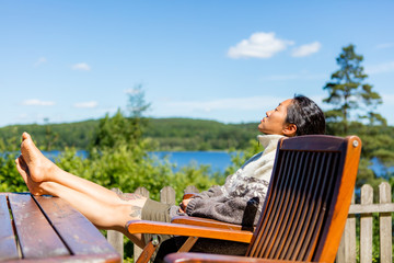 Woman relaxing in the sun on a terrace with a lake view