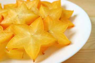 Closed up vibrant color fresh Star Fruit sliced in many pieces served on white plate 