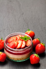 Mini  strawberry cheesecake in a glass pot on black stone background